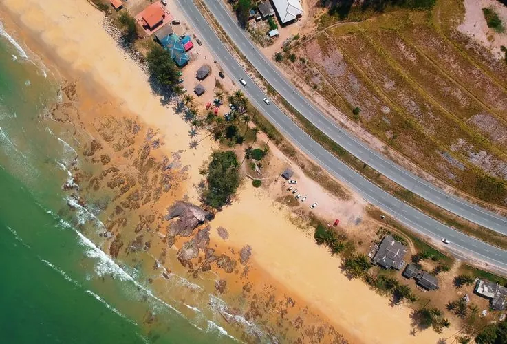 Aerial view of a scenic beach with a nearby coastal highway