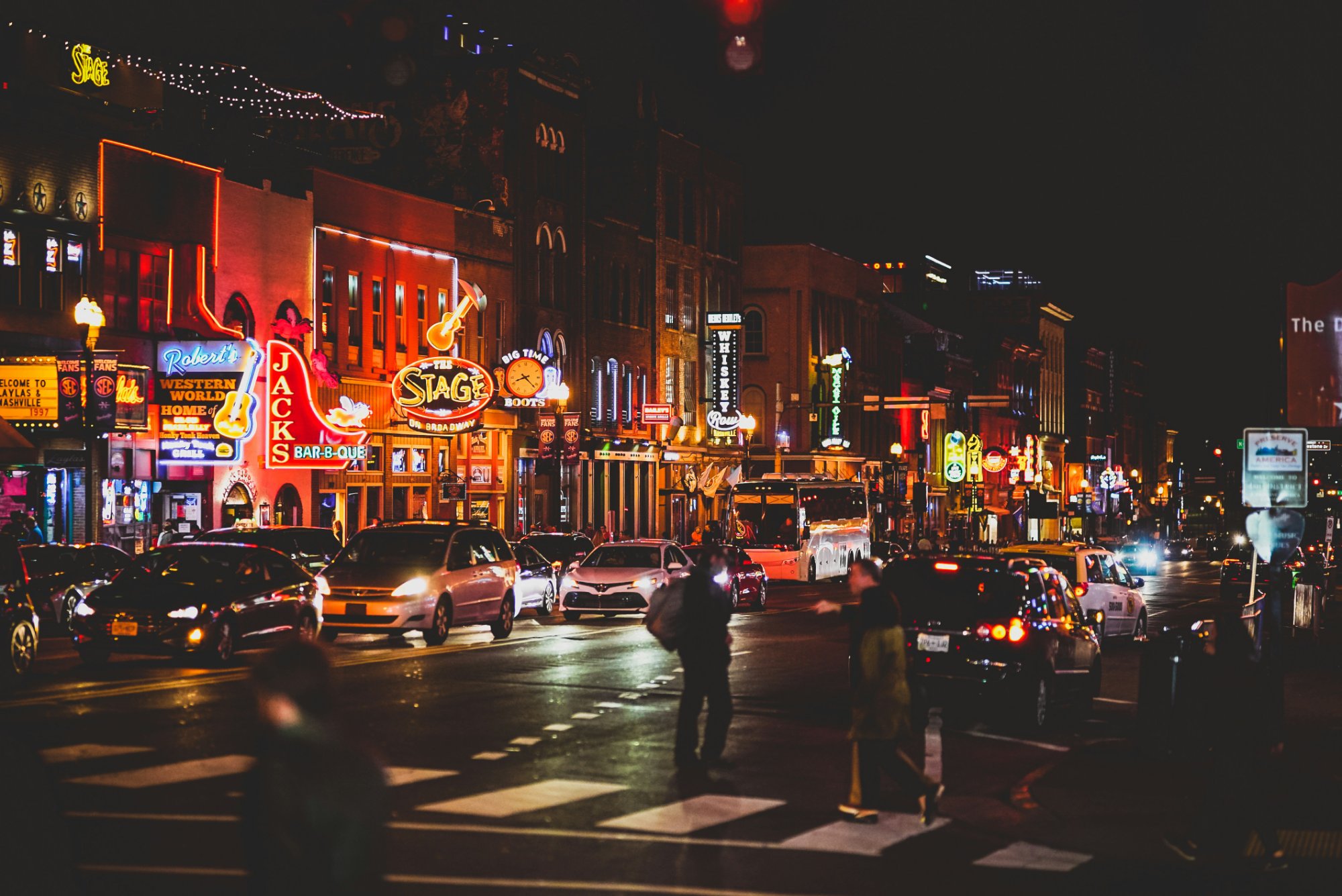 Lower Broadway Nashville at night with neon bar signs and street traffic