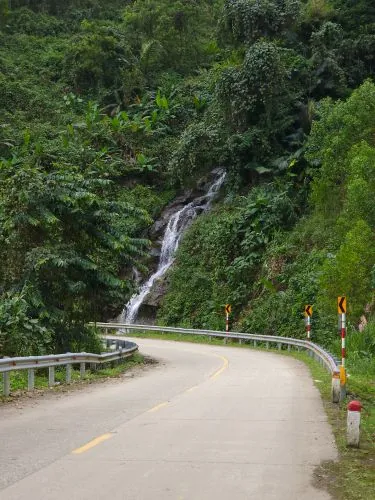 Scenic winding road past a tropical waterfall