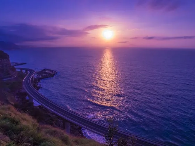 Sunrise over the ocean along a winding coastal highway